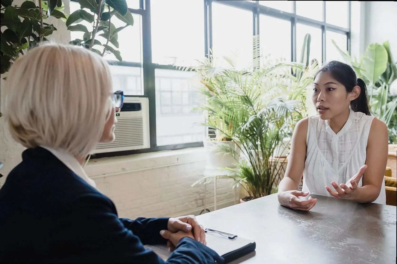 Two women engaged in a professional consultation at a modern indoor office setting.